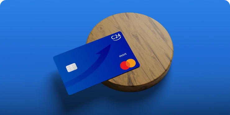 Eine dunkelblaue C24 Mastercard liegt auf einem runden Holzbrett.